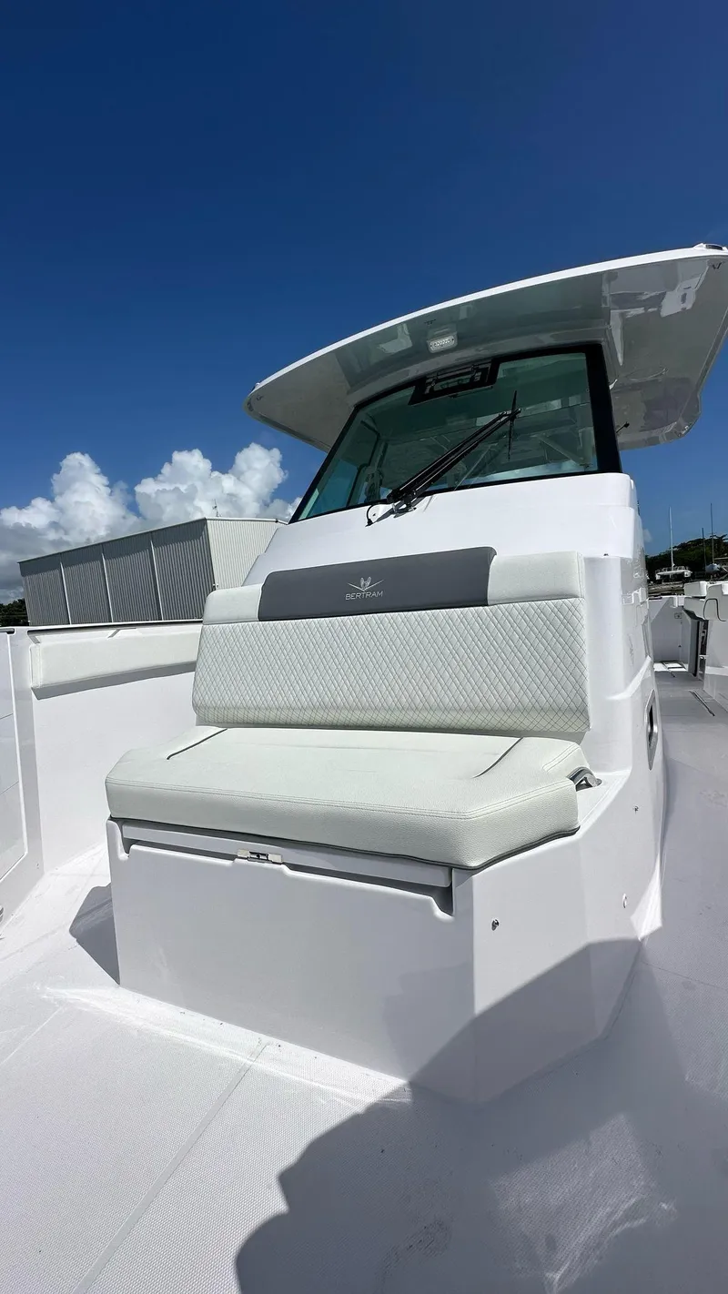 Slide: The Image of 2025 Bertram 34 CC boat with cushioned seating under a clear blue sky. - 2