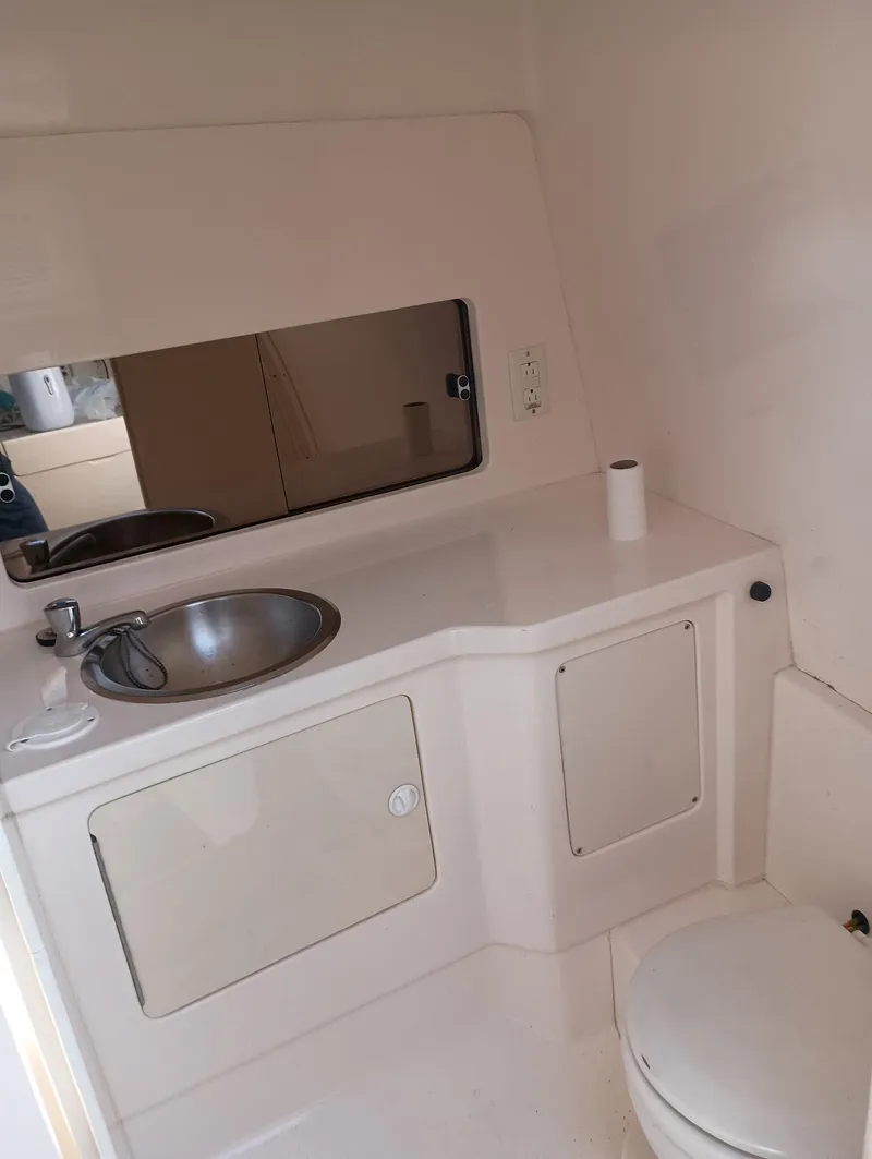 Slide: The Image of 1998 Intrepid 356 Center Console Cuddy bathroom with sink, mirror, and toilet. - 13