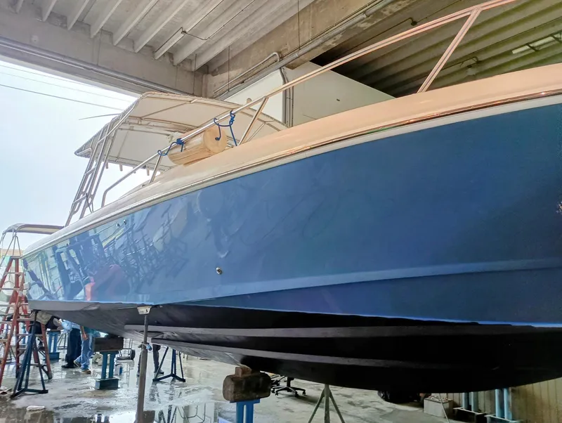Slide: The Image of 1998 Intrepid 356 Center Console Cuddy boat in a workshop, blue hull, under maintenance. - 5