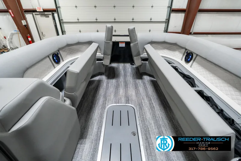 Slide: The Image of 2025 Bennington 25 LPD boat interior with gray seating and carpet, showcased in a garage. - 23
