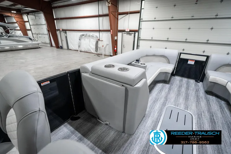 Slide: The Image of 2025 Bennington 25 LPD pontoon boat interior with gray seating in a spacious warehouse. - 24