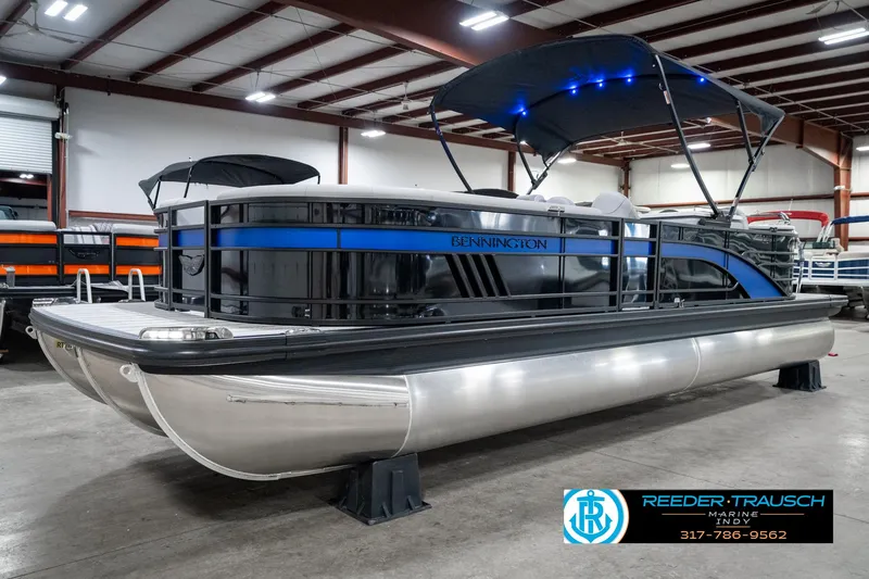 Slide: The Image of 2025 Bennington 25 LPD pontoon boat in showroom with blue accents and canopy. - 3