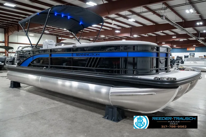 Slide: The Image of 2025 Bennington 25 LPD pontoon boat displayed indoors with blue accents and canopy. - 6