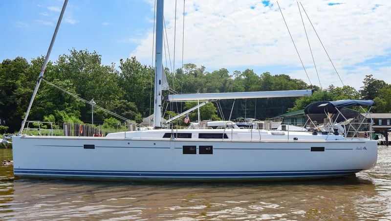Slide: The Image of 2018 Hanse 505 sailboat on calm water, surrounded by lush greenery. - 1