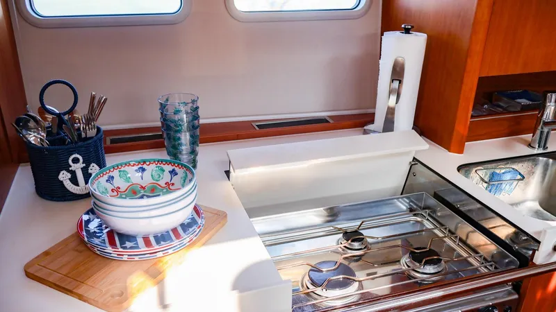 Slide: The Image of Hanse 505 yacht kitchen interior with stove, sink, and nautical-themed utensils. - 23