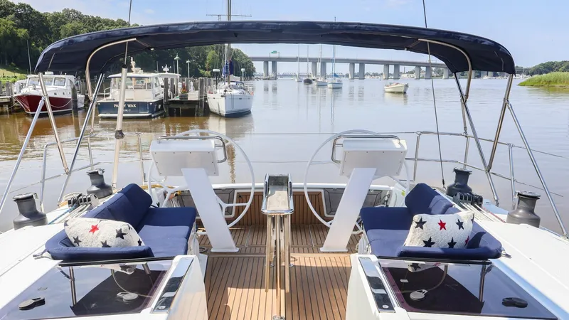Slide: The Image of 2018 Hanse 505 yacht cockpit with dual steering wheels, docked in a serene marina. - 4
