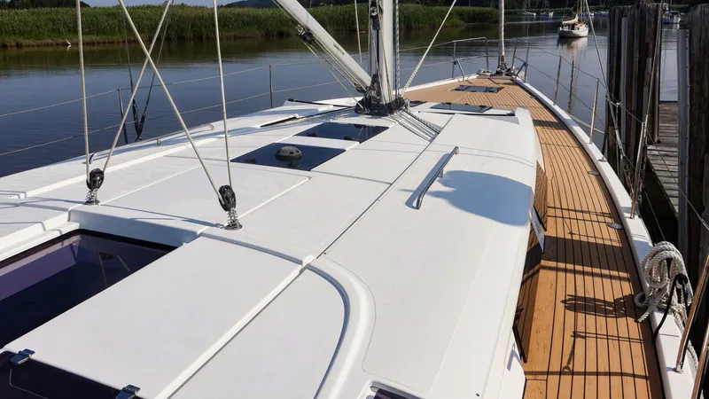Slide: The Image of 2018 Hanse 505 yacht deck with sleek design and wooden accents, docked by a calm river. - 5