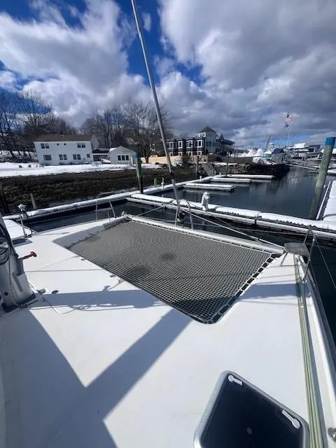 Slide: The Image of 2011 Nautitech 402 catamaran docked, featuring spacious deck and netting under cloudy skies. - 19