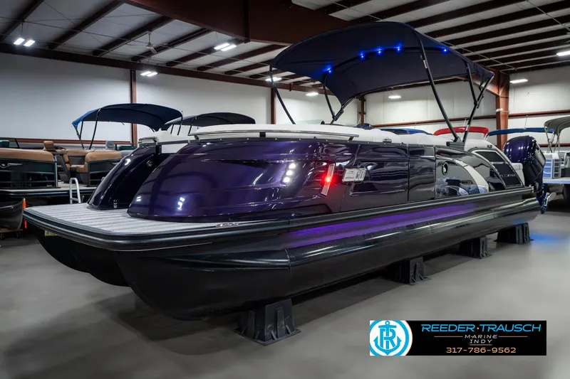 Slide: The Image of 2025 Bennington QX SB T2 pontoon boat in showroom with blue canopy lighting. - 3