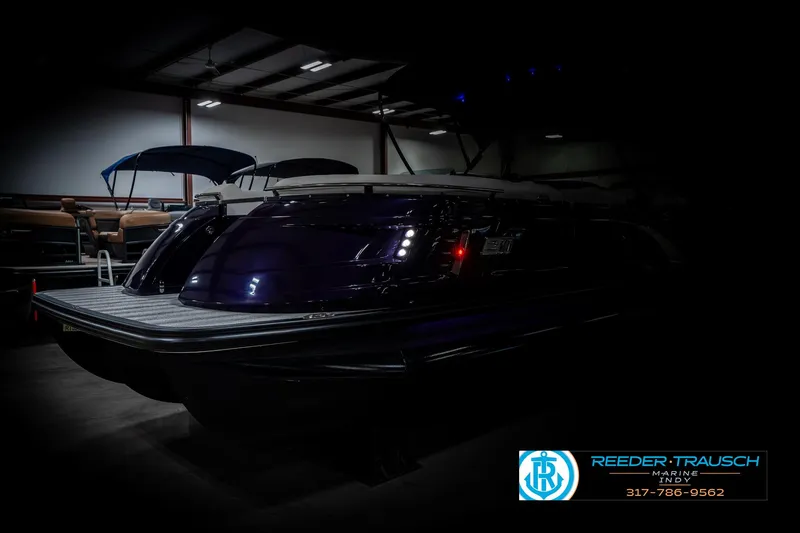 Slide: The Image of 2025 Bennington QX SB T2 boat in a dimly lit showroom. - 4