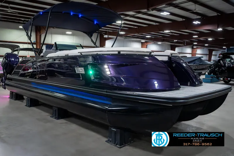 Slide: The Image of 2025 Bennington QX SB T2 pontoon boat displayed indoors with blue LED lights. - 6