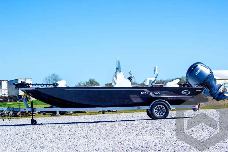 Slide: The Image of 2025 G3 Bay 21 GX boat on trailer, parked outdoors under clear blue sky. - 11