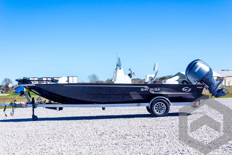Slide: The Image of 2025 G3 Bay 21 GX boat on trailer, parked on gravel, under clear blue sky. - 19