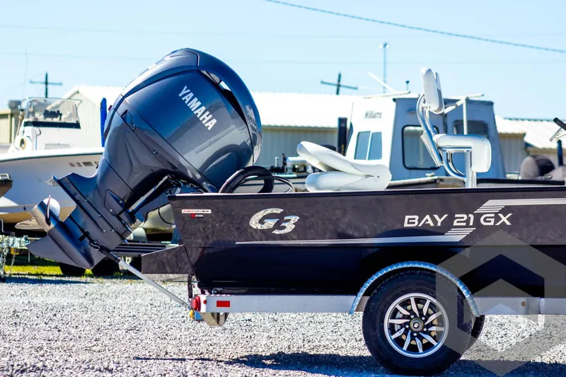 Slide: The Image of 2025 G3 Bay 21 GX boat with Yamaha outboard motor, parked on gravel. - 6