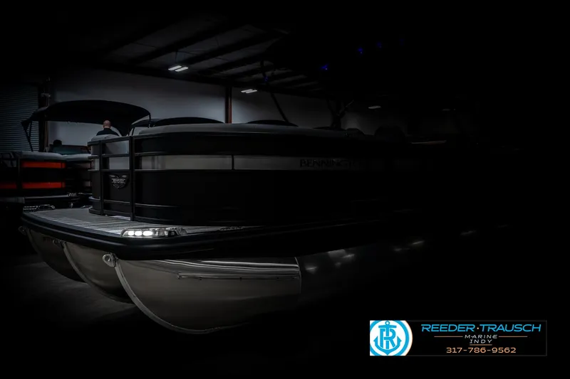 Slide: The Image of 2025 Bennington 23 LPD pontoon boat in a dimly lit showroom. - 4