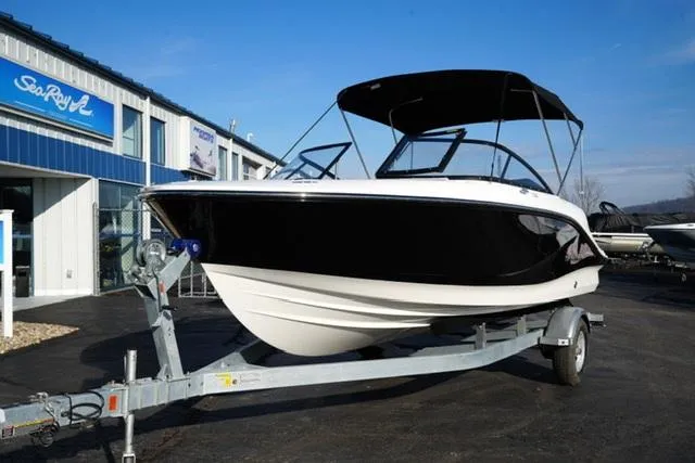 The Image of 2025 Bayliner V20 boat on trailer, parked outside a dealership under clear blue sky. - 1