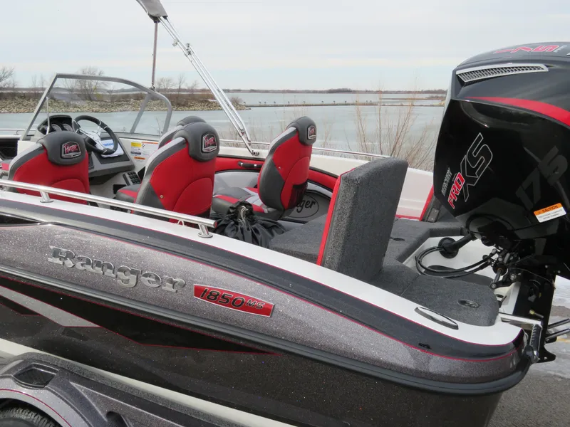 Slide: The Image of 2025 Ranger 1850MS boat with red and black seating, docked by a lake. - 3