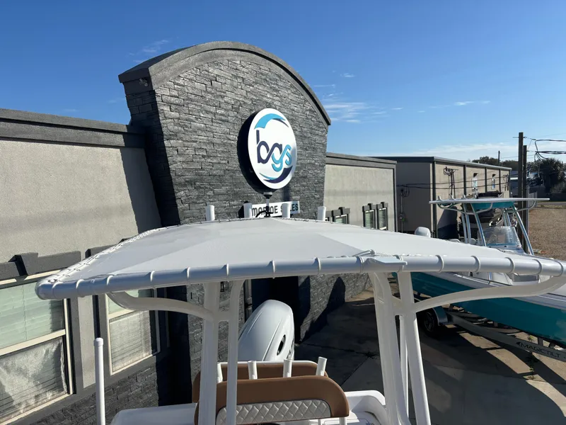 Slide: The Image of 2024 Clearwater 21 Bay boat outside a building with a logo, under a clear blue sky. - 1