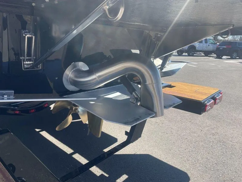 Slide: The Image of 2025 Moomba Max boat stern with propeller and exhaust system in a parking lot. - 11