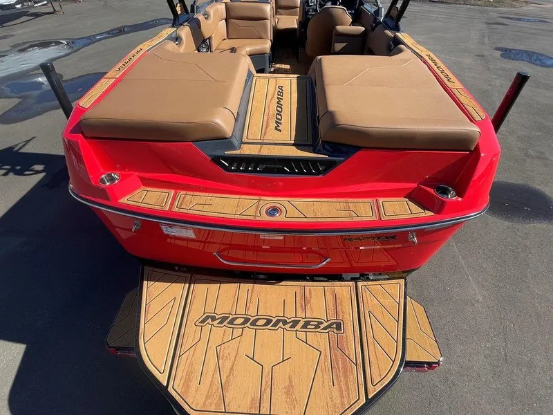 Slide: The Image of 2025 Moomba Max boat, red exterior, tan seating, wood accents, rear view. - 13