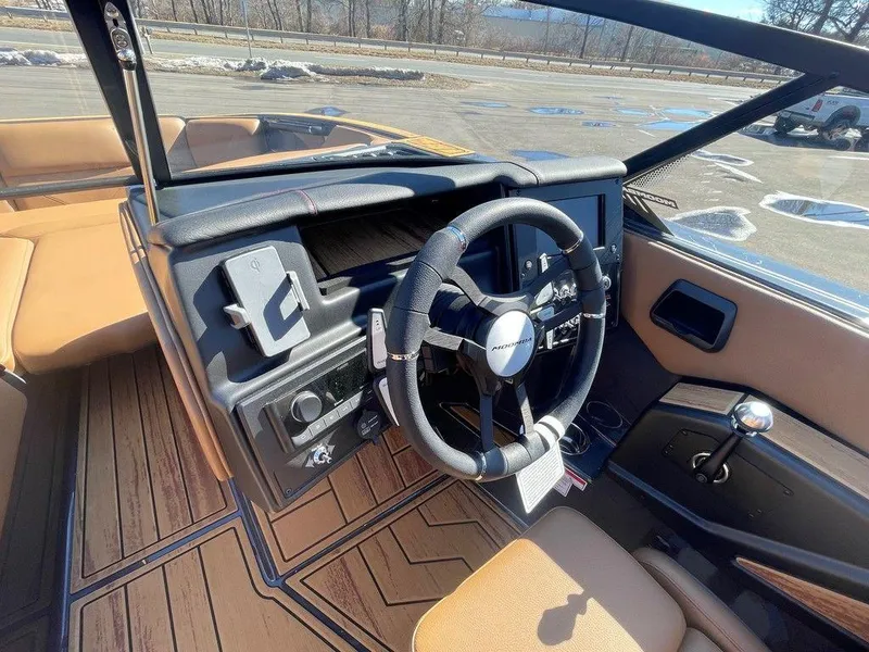 Slide: The Image of 2025 Moomba Max boat interior with steering wheel and dashboard, featuring wood accents. - 22