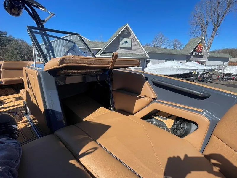 Slide: The Image of 2025 Moomba Max boat interior with tan seating, outdoor setting, and clear blue sky. - 38