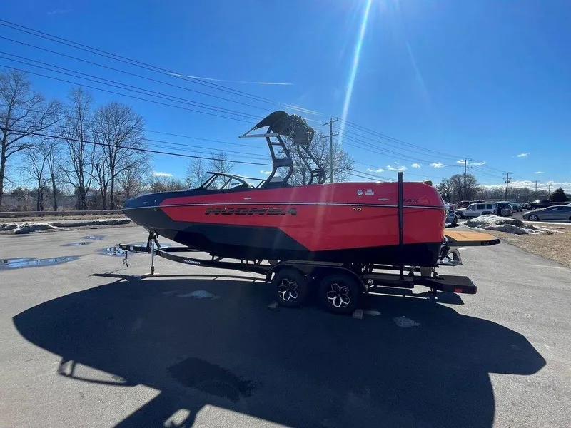 Slide: The Image of 2025 Moomba Max boat on trailer, red and black design, parked outdoors under clear blue sky. - 4