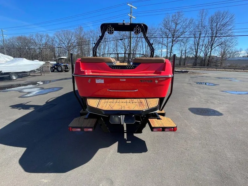 Slide: The Image of 2025 Moomba Max boat, red, rear view, parked on asphalt, clear sky background. - 8