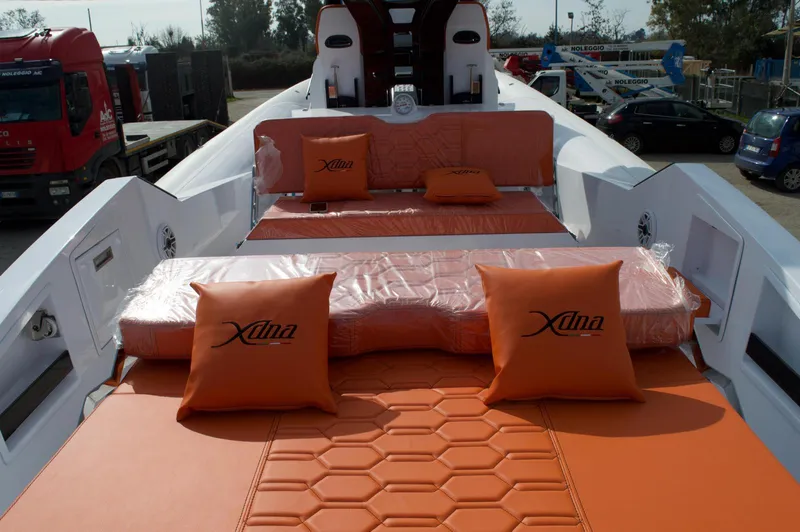 Slide: The Image of Luxurious DNA 46 yacht interior with orange cushions, 2025 model, docked outdoors. - 2