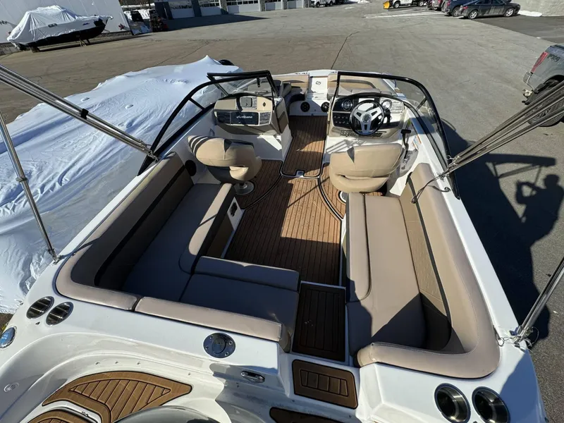 Slide: The Image of 2018 Hurricane SunDeck 217 OB boat interior with seating and steering wheel, parked outdoors. - 6