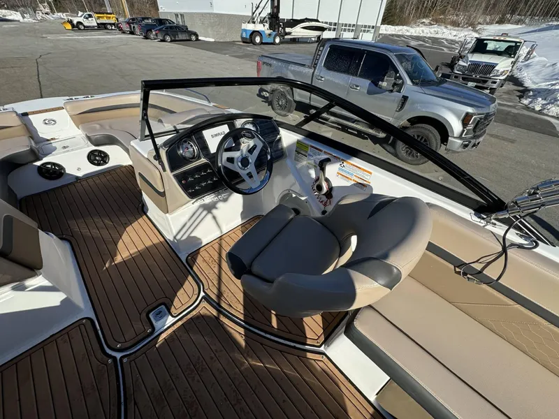 Slide: The Image of 2018 Hurricane SunDeck 217 OB boat interior with steering wheel and seating, parked near vehicles. - 8