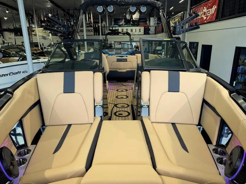 Slide: The Image of 2025 MasterCraft X24 boat interior with tan and black seating in showroom. - 14