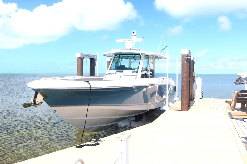 Slide: The Image of 2022 Boston Whaler 380 Outrage docked by the sea under a clear blue sky. - 4