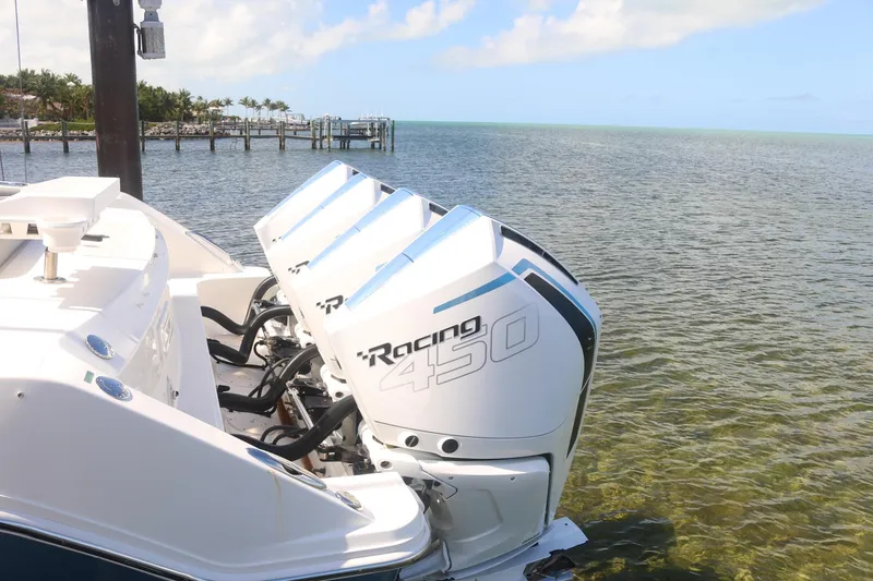Slide: The Image of 2022 Boston Whaler 380 Outrage with triple Racing 450 engines on a serene water backdrop. - 6