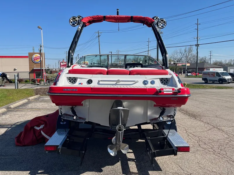 Slide: The Image of 2024 Crownline 220 SS SURF boat, red and white, parked outdoors, rear view. - 10