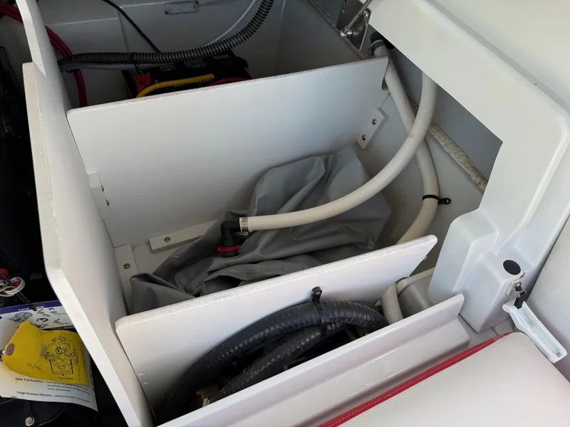 Slide: The Image of Storage compartment in 2024 Crownline 220 SS SURF boat, featuring hoses and equipment. - 14