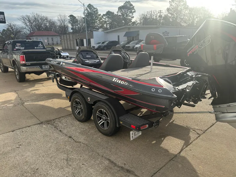 Slide: The Image of 2023 Triton 18 TrX boat on trailer, parked outdoors, with a pickup truck nearby. - 1