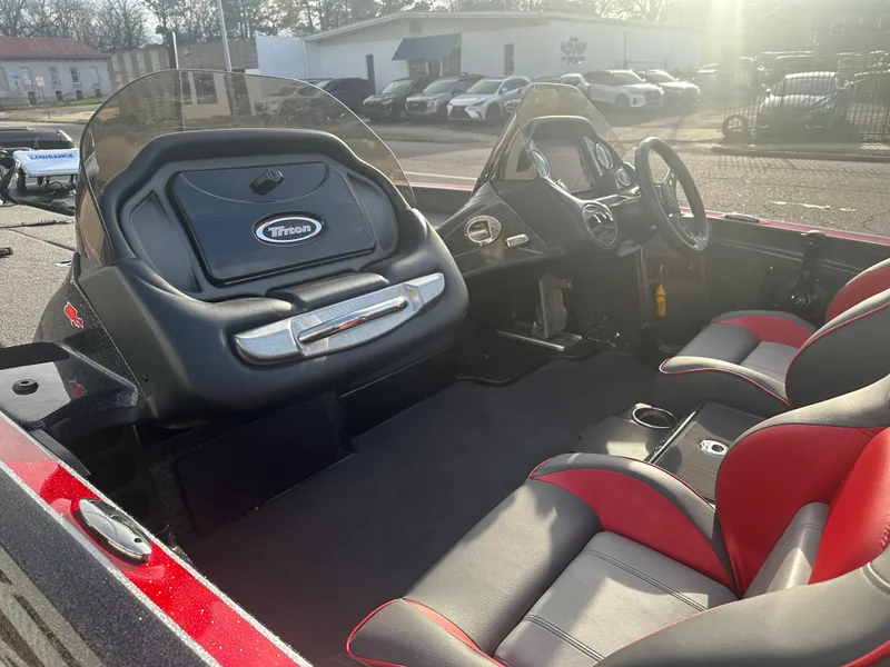 Slide: The Image of 2023 Triton 18 TrX boat interior with black and red seating, steering console, and dashboard. - 10