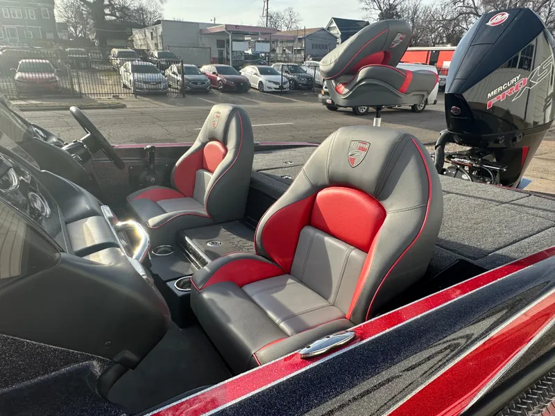 Slide: The Image of 2023 Triton 18 TrX boat interior with red and gray seats, parked outdoors. - 11