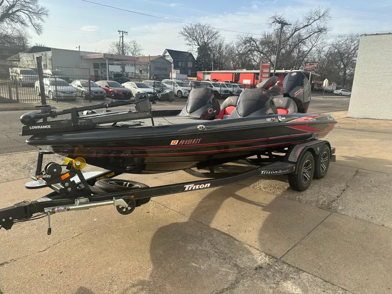 Slide: The Image of 2023 Triton 18 TrX bass boat on trailer, parked outdoors. - 2