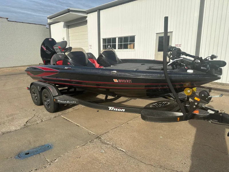 Slide: The Image of 2023 Triton 18 TrX bass boat on trailer, parked outside a building. - 3