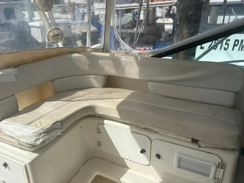 Slide: The Image of 1995 Tiara Yachts 3600 Open interior seating with beige cushions and storage compartments. - 5
