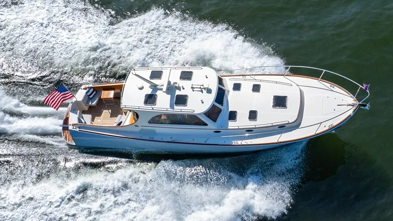 Slide: The Image of 2008 Hinckley Talaria 44 yacht cruising on open water, displaying sleek design and American flag. - 16