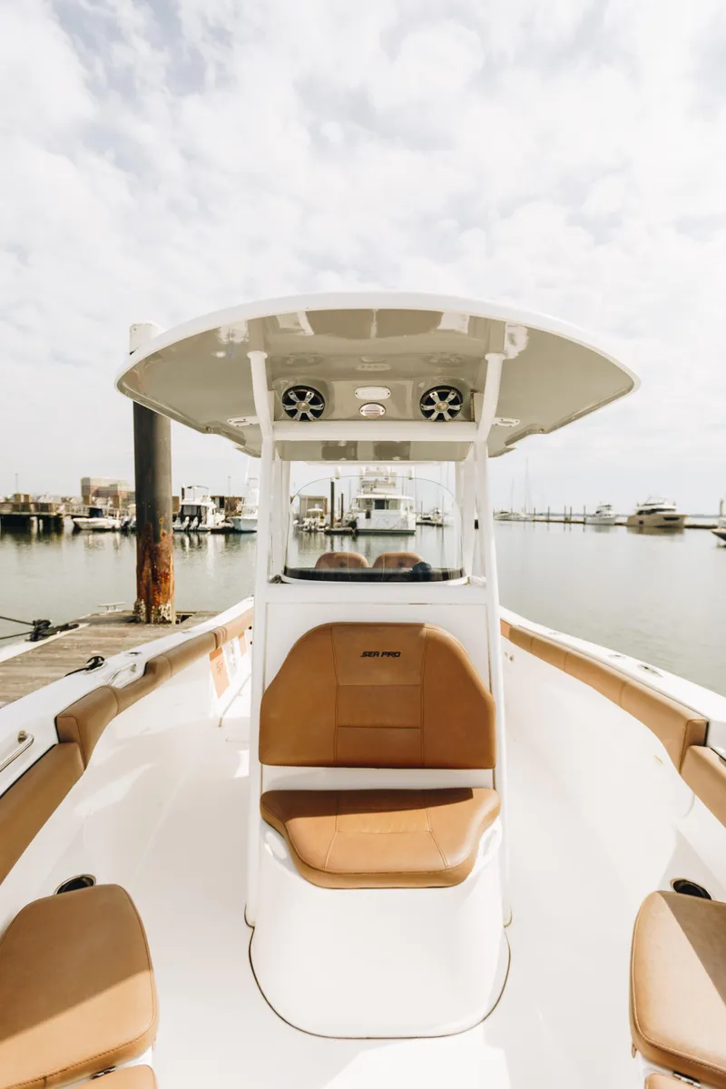Slide: The Image of 2019 Sea Pro 259 Center Console boat docked at a marina under a cloudy sky. - 13