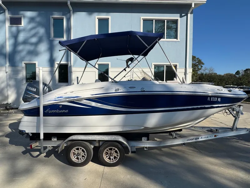 Slide: The Image of 2012 Hurricane SunDeck Sport 200 OB boat on trailer, blue and white design, parked outdoors. - 14