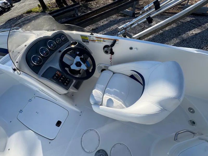 Slide: The Image of 2012 Hurricane SunDeck Sport 200 OB boat cockpit with steering wheel and white captain's chair. - 7