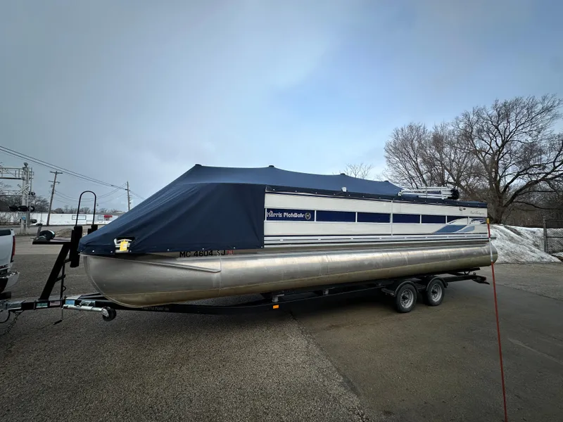 Slide: The Image of 2003 Harris FloteBote 260 Royal Heritage pontoon boat on trailer, covered and parked outdoors. - 1