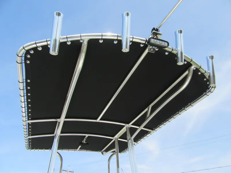 Slide: The Image of T-top of 2025 Parker 18SE Center Console boat with rod holders against blue sky. - 3