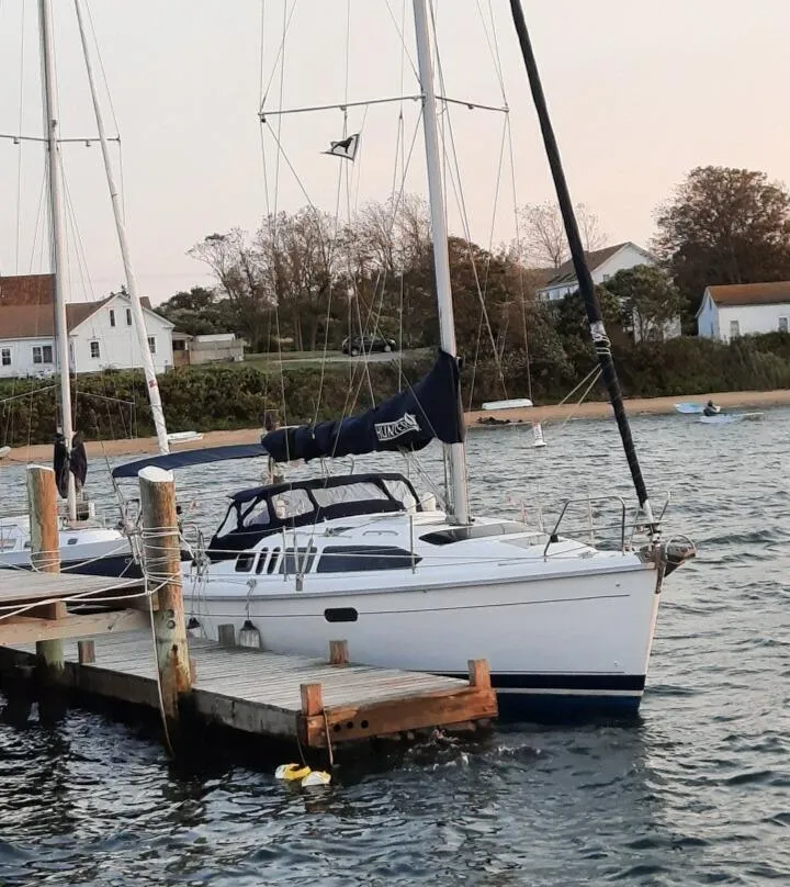Slide: The Image of Hunter 336 sailboat docked by the shore, 1995 model, with scenic coastal background. - 2