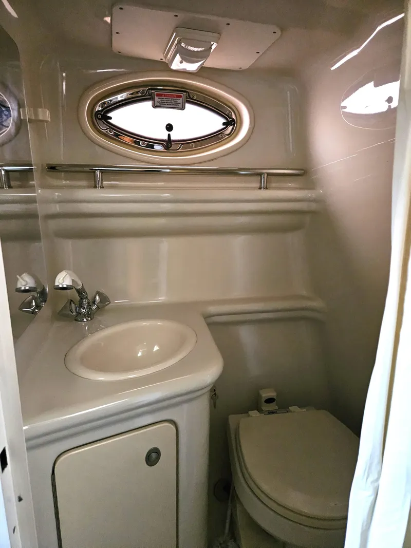 Slide: The Image of 2006 Sea Ray 270 Amberjack boat bathroom with sink, toilet, and porthole window. - 13